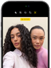 iPhone 18 Pro i fargen svart vises forfra, to modeller poserer for kameraet, for å vise Center Stage-frontkameraet